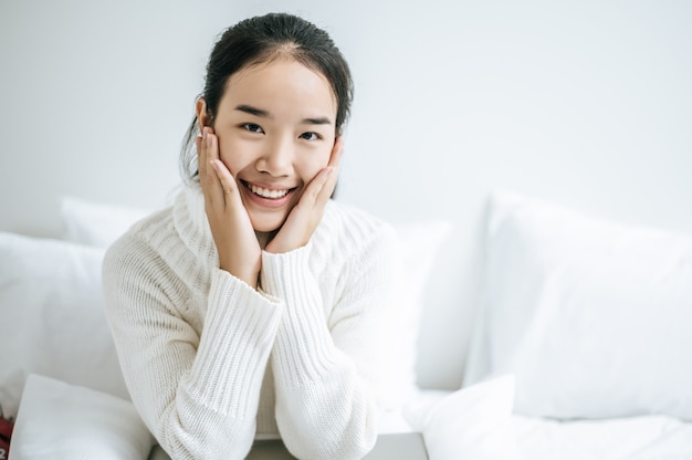 A woman sitting and hands touching cheeks.