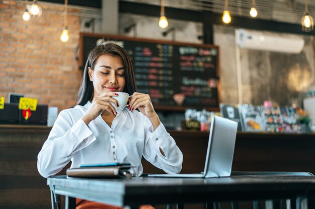 woman sitting happily drinking coffee in cafe shop and laptop