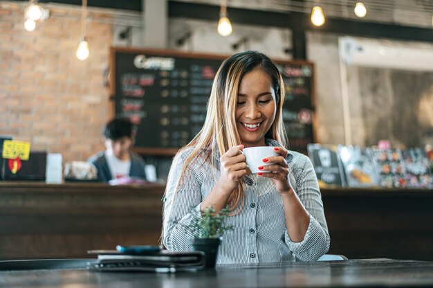 カフェでコーヒーを飲んで喜んで座っている女性