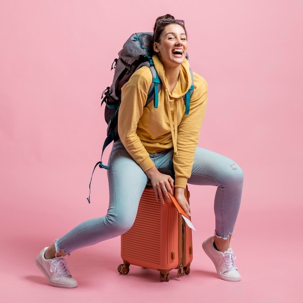 Woman sitting on her baggage while laughing