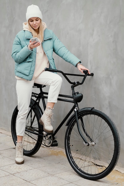 Woman sitting on her bike and using her mobile phone