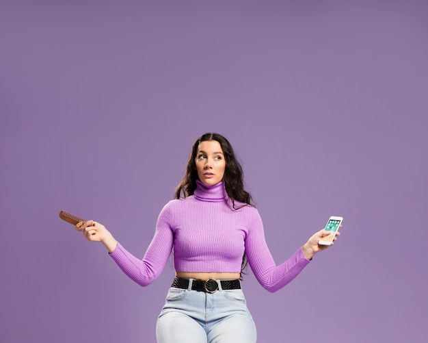 Free photo woman sitting and holding mobile phone and comb