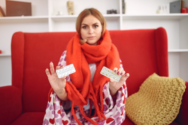 Woman sitting at home with a cold and taking pills