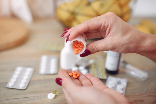 Woman sitting at home with a cold and taking pills