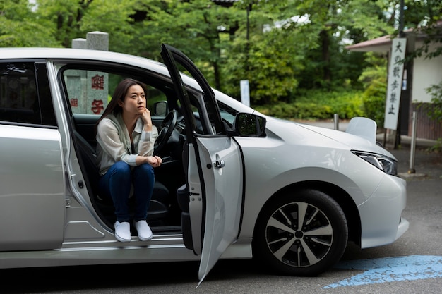 무료 사진 그녀의 전기 자동차에 앉아있는 여자