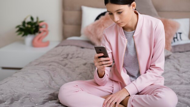 Foto gratuita donna seduta al chiuso e utilizzando il telefono cellulare