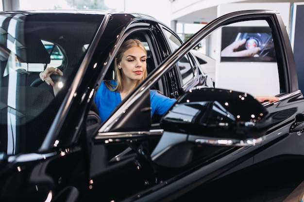 Woman sitting inside a car in a car showroom