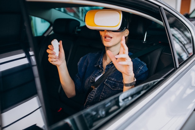 Foto gratuita donna che si siede dentro un'automobile che indossa i vetri del vr