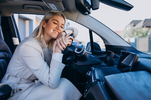 充電しながら電気自動車の中に座っている女性