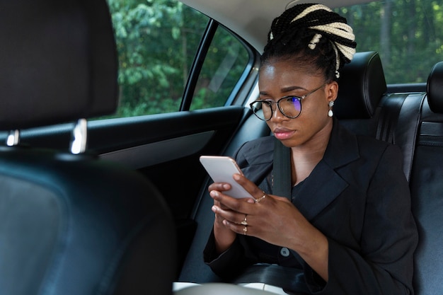 Free photo woman sitting inside her car and looking at smartphone