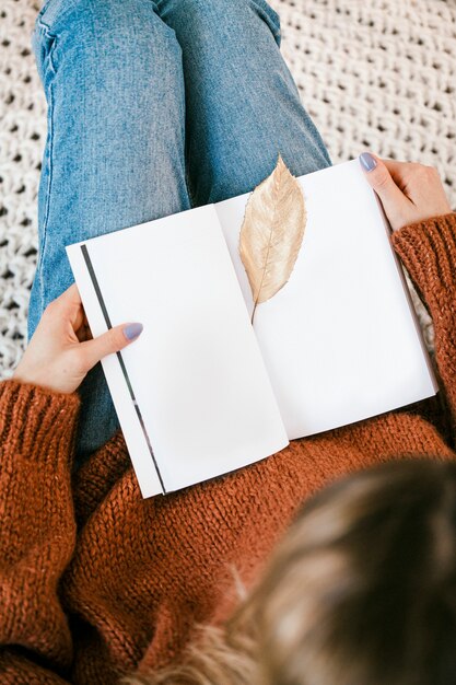 Woman sitting on a knitted rug with a golden crisp leaf on an open notebook