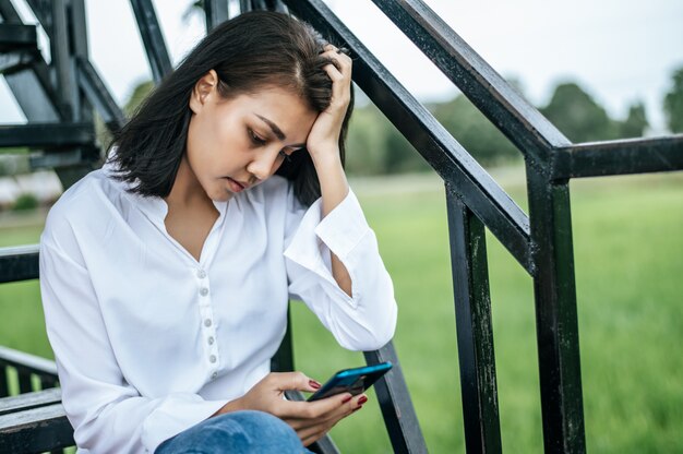 Woman sitting on a ladder looking at a smart phone and having stress