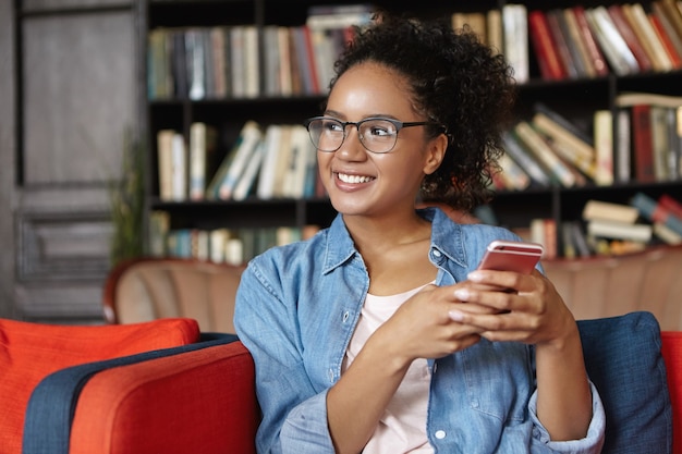 Free photo woman sitting in a library with her phone