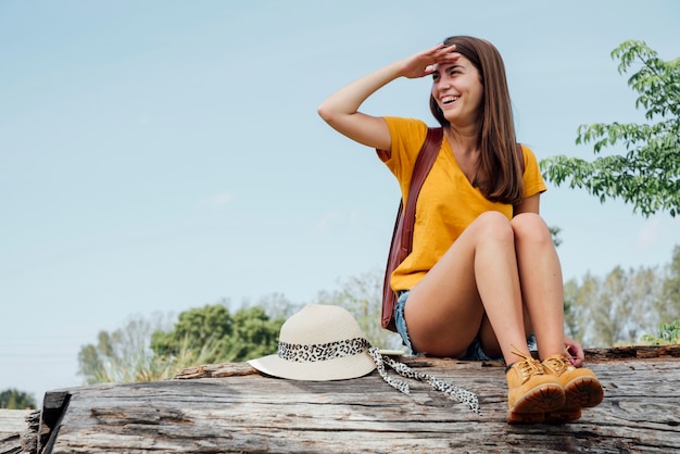 Woman sitting on log and looking away