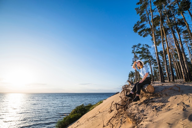 Free photo woman sitting on log and looking at distance