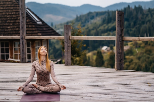 A woman sitting in lotus position at the morning on a fresh air.