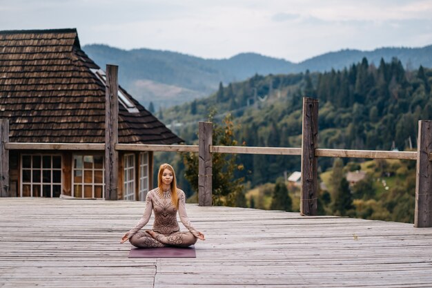 A woman sitting in lotus position at the morning on a fresh air.