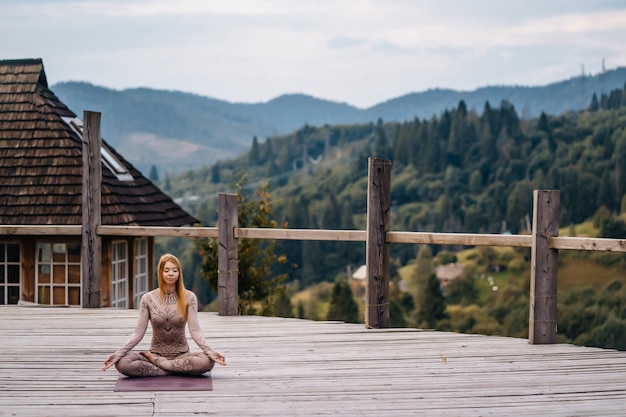 Free photo a woman sitting in lotus position at the morning on a fresh air.