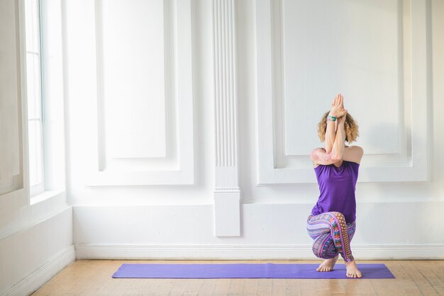 Woman sitting and meditating on mat