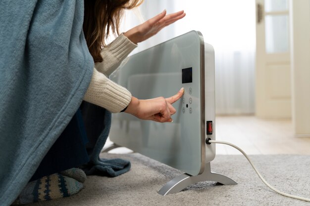 Woman sitting near heater at home