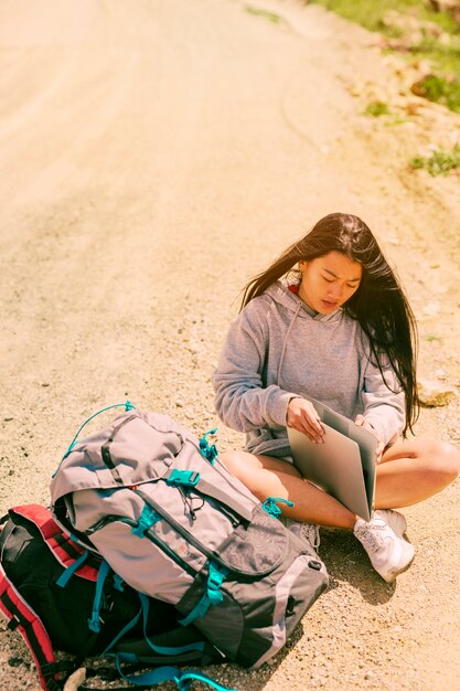 無料写真 道路上に座っているとバックパックの中でラップトップに取り組んでいる女性