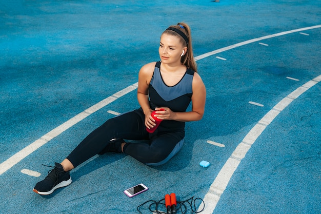 Woman sitting on the playground with a bottle of water