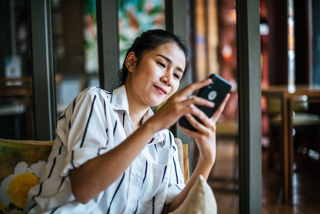 女性が座っているとカフェで彼女のスマートフォンをプレイ