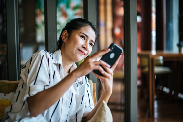 女性が座っているとカフェで彼女のスマートフォンをプレイ