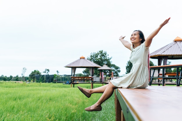 Woman sitting and relax on Wood bridge with their legs hanging down