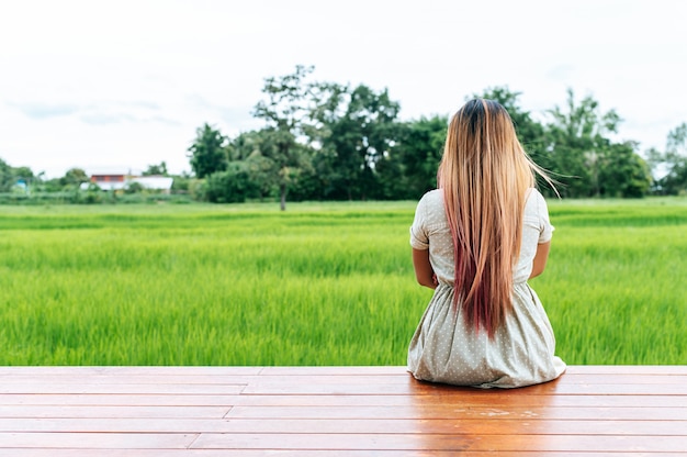 Woman sitting and relax on Wood bridge with their legs hanging down