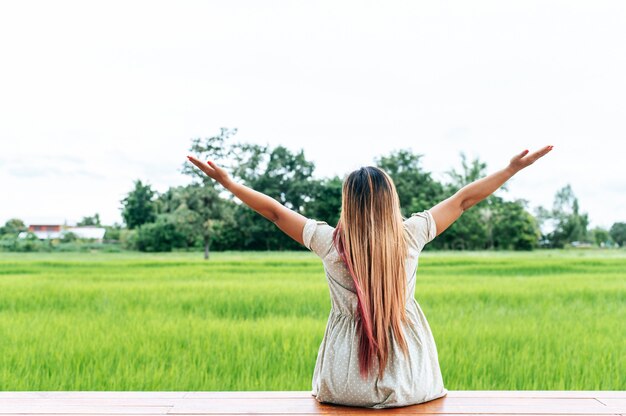 Woman sitting and relax on Wood bridge with their legs hanging down