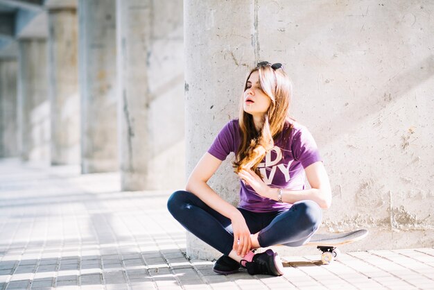 Woman sitting and resting on skateboard