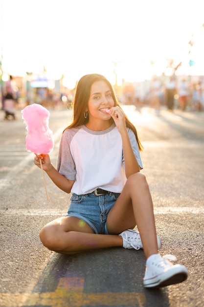 綿菓子を食べて道路に座っている女性