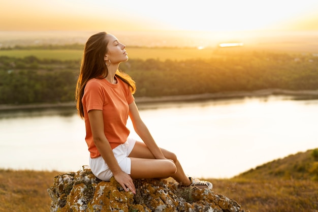 Free photo woman sitting on rock side view