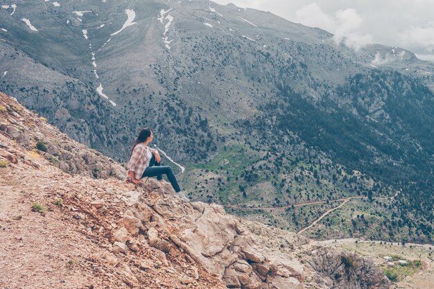 岩の上に座って、景色を楽しみながら、昼間に丘で考える女性