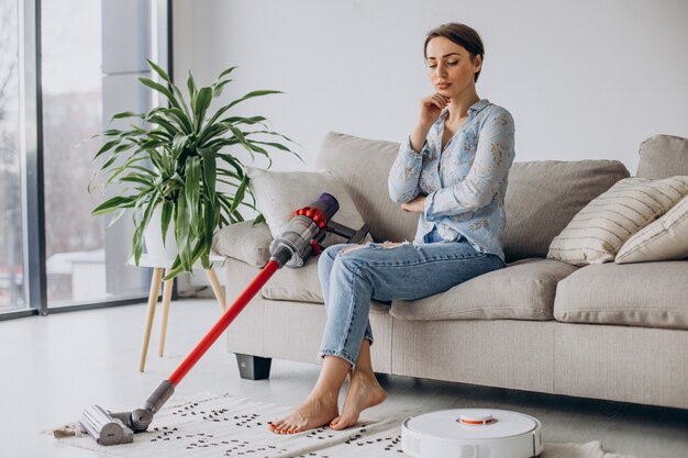 Woman sitting on sofa and choosing vacuum cleaner