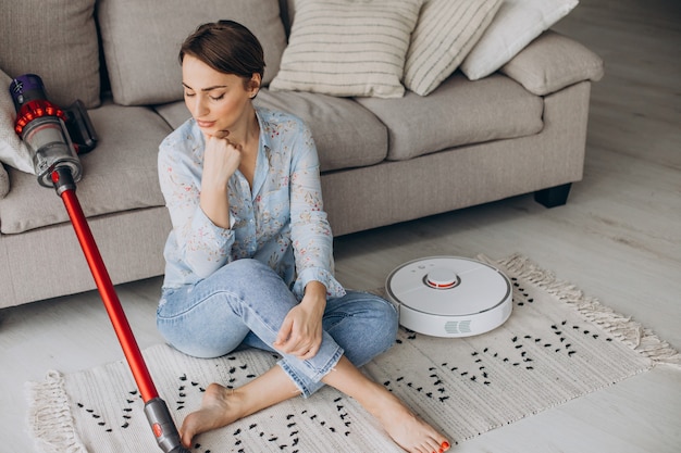 Free photo woman sitting on sofa and choosing vacuum cleaner