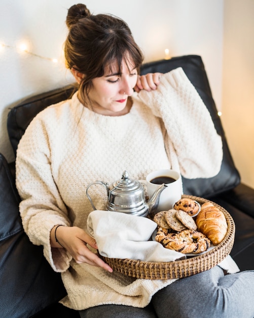 トレー、食べ物でソファーに座っている女性