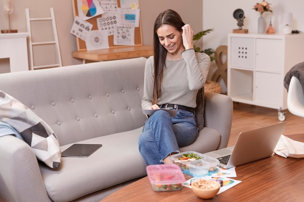 Free photo woman sitting on a sofa and works