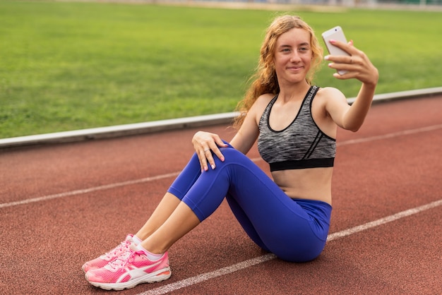 Woman sitting on stadium and taking selfie 