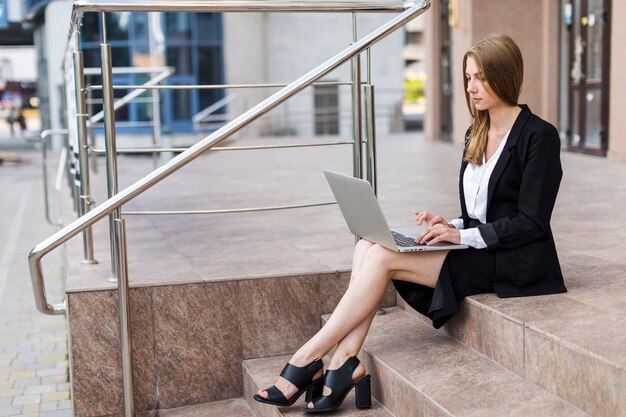 Женщина сидит на лестнице, используя свой ноутбук