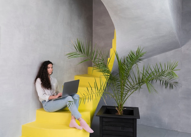 Woman sitting on the stairs using the laptop