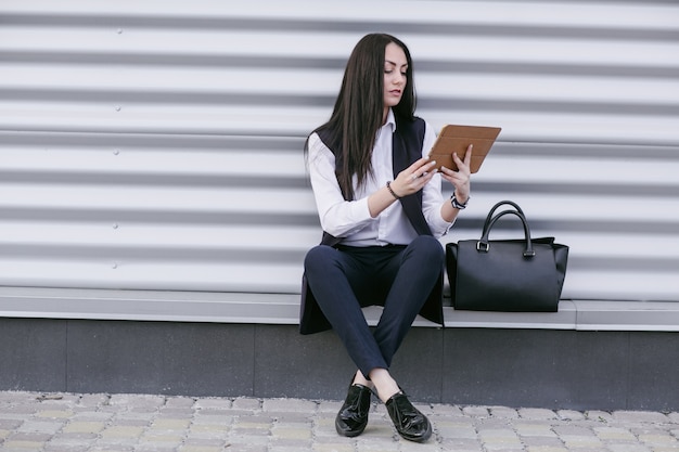 Free photo woman sitting on a step and looking at a tablet