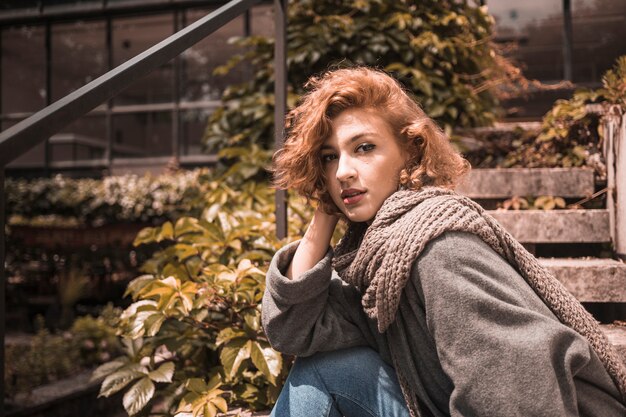 Free photo woman sitting on steps in coat and scarf