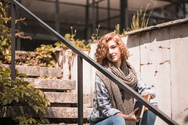 Foto gratuita donna che si siede sui gradini e che tiene i libri