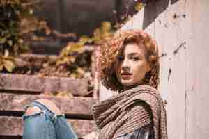 Free photo woman sitting on steps in knitted scarf