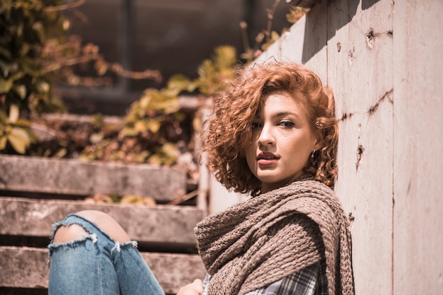 Woman sitting on steps in knitted scarf