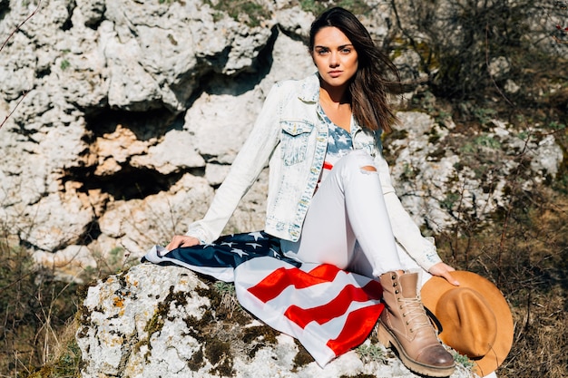 Free photo woman sitting on stone with american flag