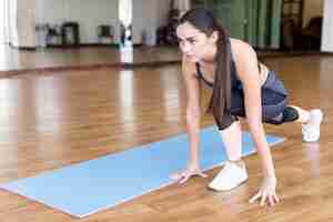 Free photo woman sitting and stretching in gym