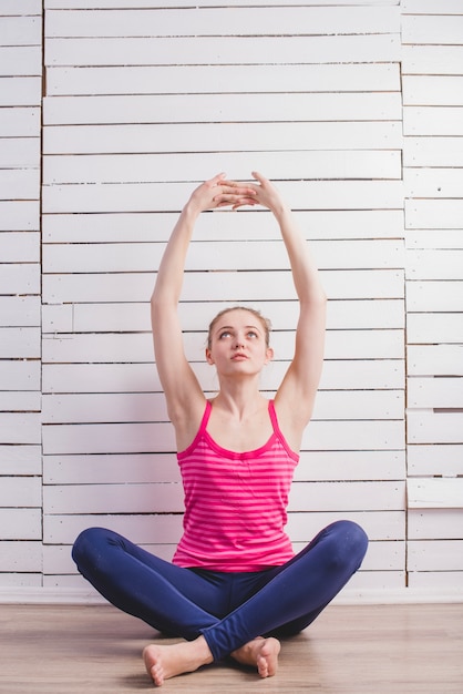 Free photo woman sitting and stretching at wall